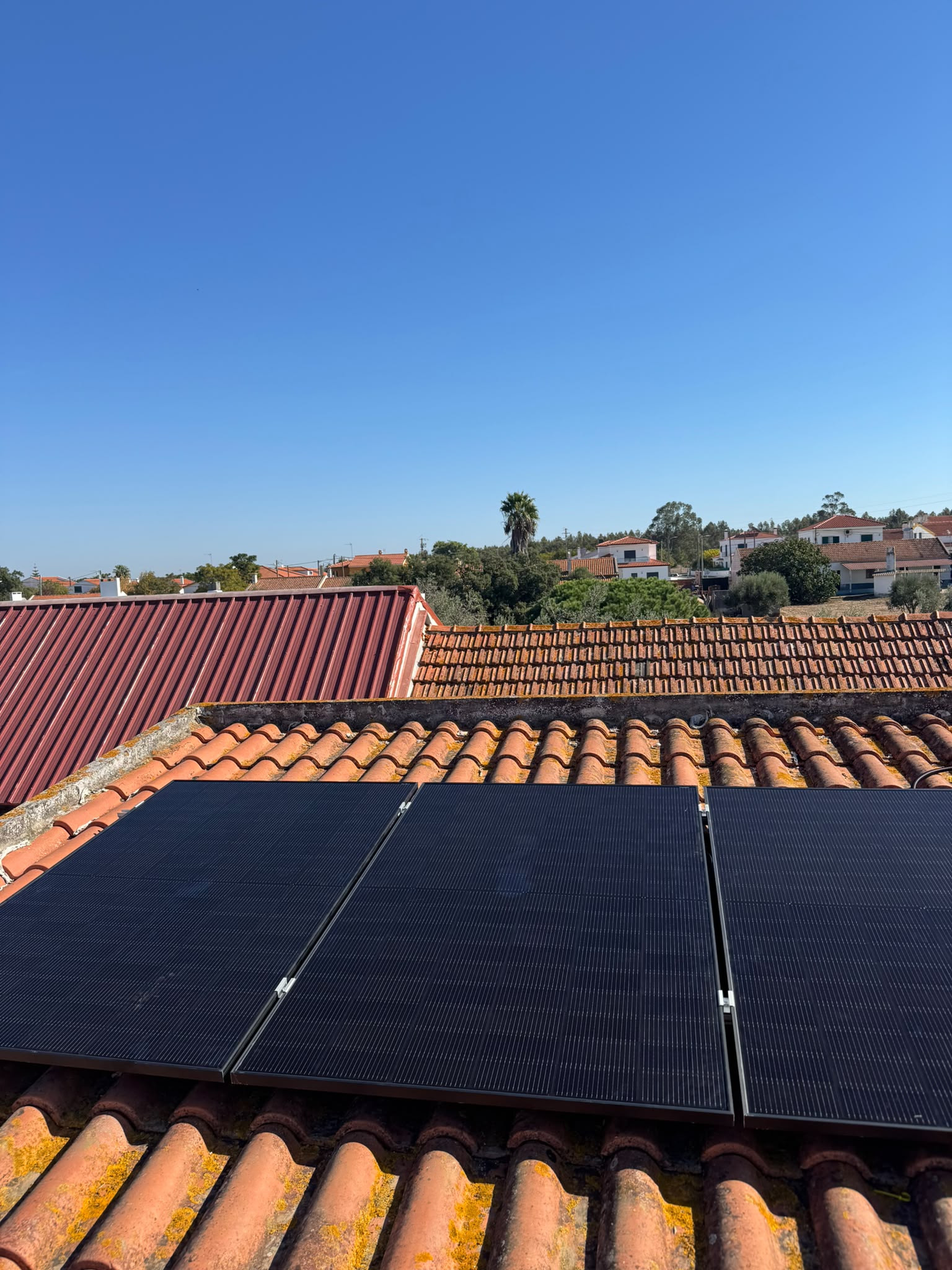 Painéis solares sobre um telhado de telha, com céu azul